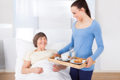 caregiver assisting woman in bed to eat